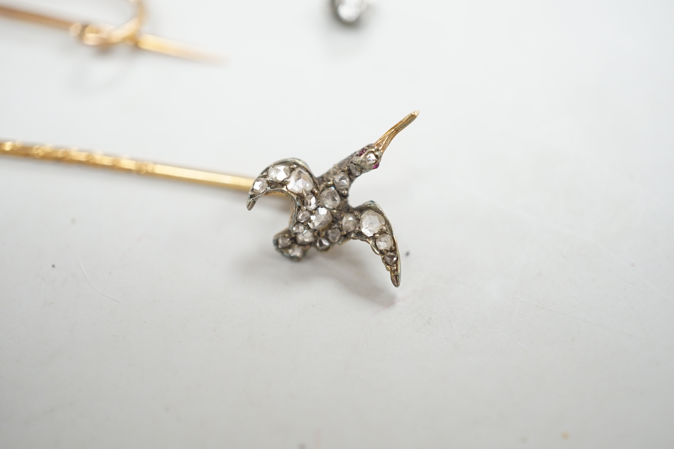 An Edwardian 15ct riding crop brooch(a.f.), 59mm, 2.8 grams, an 18ct hunting horn brooch (lacking pin) 2.1 grams, two Victorian diamond cluster set stick pins including swan in flight, a diamond set pin terminal, gross 4